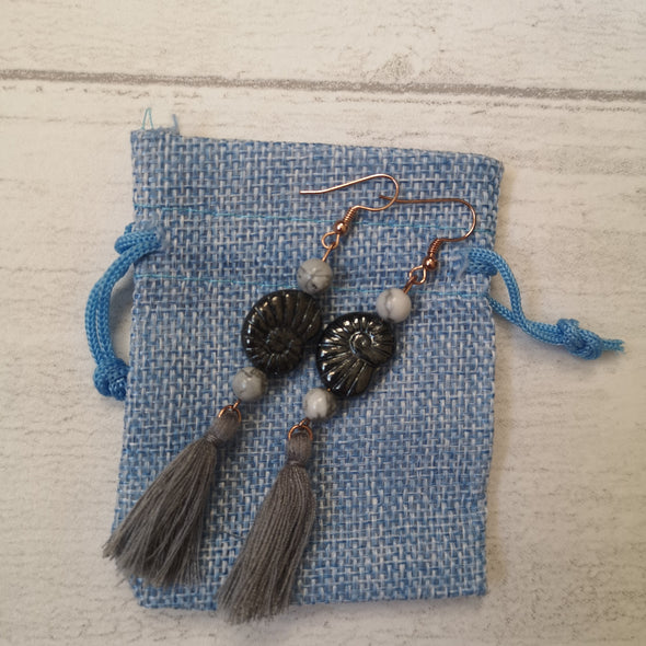 Grey vintage fossil shell and tassel statement earrings on blue hessian bag