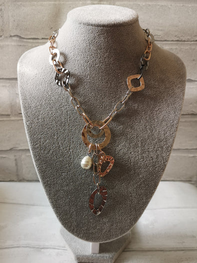 Long rose gold and silver necklace on a grey stand