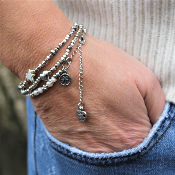 Set of 3 silver and pearl bracelets being worn on wrist