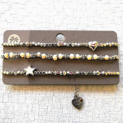 Three silver and pearl bracelets with star and heart on card 